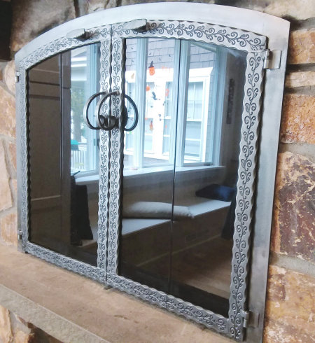 Horizon  (on Stone)  All natural iron finish,  scrolled steel vice bi fold doors, with standard forged center handles, and smoked glass. Comes with gate mesh spark screens.  (mortar installation)